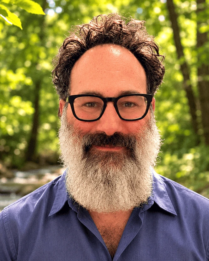 Moishe Goldstein, founder, photographed outdoors beside a creek.